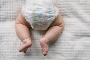 A baby in a diaper at the age of two months and a stack of diapers. How to choose baby diapers