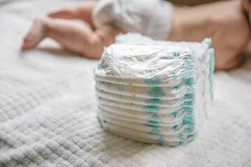A baby in a diaper at the age of two months and a stack of diapers. How to choose baby diapers