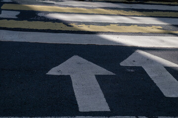 Two white arrows on the pavement indicate the beginning of the crosswalk in the form of white and yellow stripes. View from above