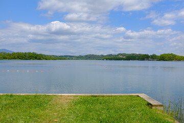 Blue water lake with green grass shore on a sunny landscape in Banyoles, Catalonia