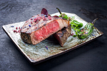 Barbecue dry aged wagyu roast beef steak with paprika and herbs as closeup on a rustic modern design plate
