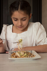 Little girl in a white dress eats in the kitchen