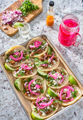tray of carne asada tacos topped with pickled onions and cojita cheese