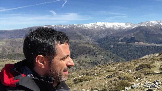Uomo cammina in montagna vicino a delle vette innevate