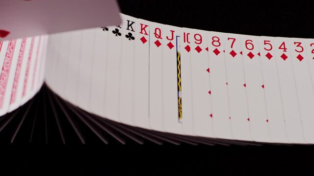 Ribbon of playing cards get turned around with another card (close-up)