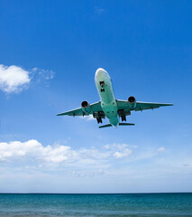 Fototapeta na wymiar a passenger plane lands low over the sea, at an airport near the beach on a Sunny day