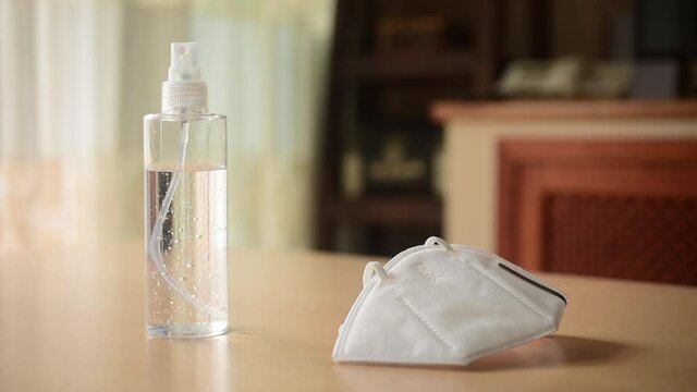 gel desinfectante con mascarilla KN95, en una mesa y muebles de fondo.