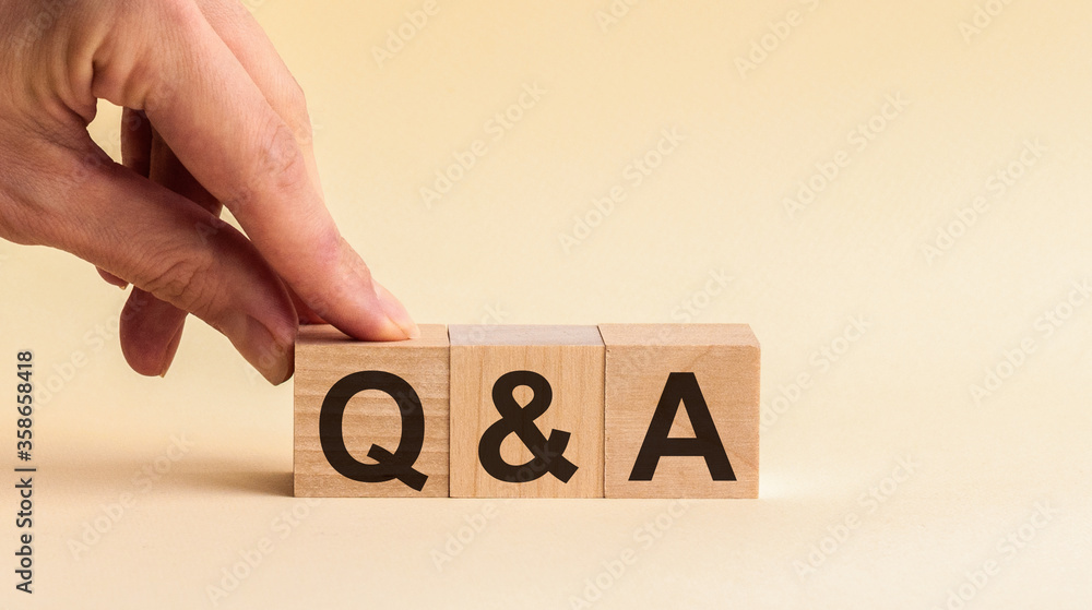 Aufkleber questions and answers concept. hand putting wood block cube with alphabet q a on table. yellow backg