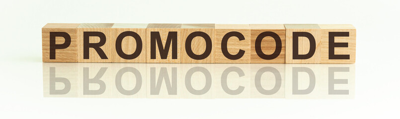 Wooden Blocks with the text: PROMOCODE. The text is written in black letters and is reflected in the mirror surface of the table. New business relaunch startup concept.
