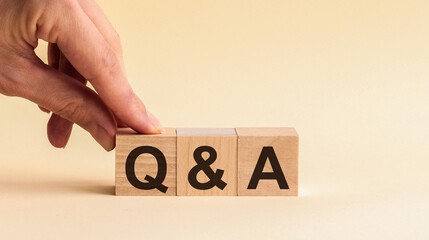 Questions and answers concept. Hand putting wood block cube with alphabet Q A on table. Yellow...