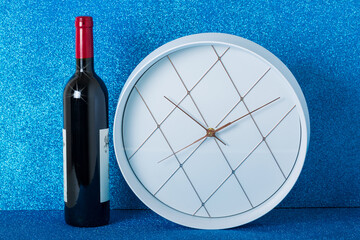 Wine bottle, white wall clock on a sparkling blue background