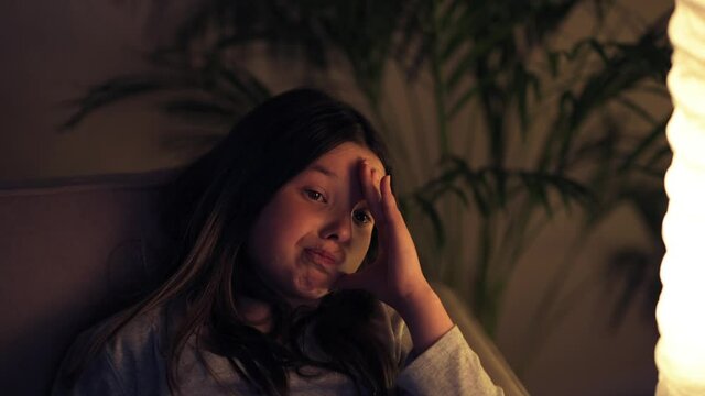 The girl is watching a non-interesting, old movie sitting at home on the couch.