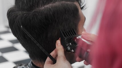 Cutting man hair with trimmer in salon. Handsome man is getting trendy haircut