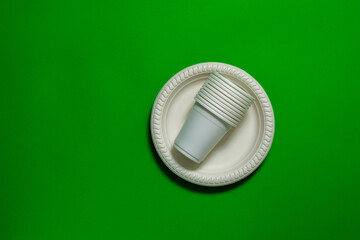 disposable eco-friendly glasses lie in corn starch plates on a green background. biodegradable dishes. replacement plastic. chromakey.