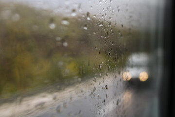 raindrops on a window and a car passing by in the background