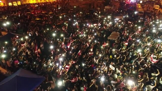 Beirut, Lebanon 2019 : night drone shot of Martyr square, during the Lebanese revolution, with protesters waving with their phones flashlights and thousands of people revolting against government