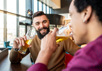 Two male friends drinking beer and talking to eachother