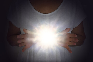 Healing Energy Phenomenon - female in white tunic with hands apart at chest level with a bright...