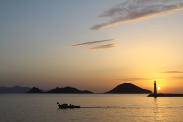 Seascape at sunset. Lighthouse on the coast. Seaside town of Turgutreis and spectacular sunsets