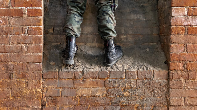Solider on war. Military black shoes on bricks old ruin. During shot.