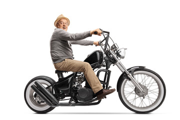 Obraz premium Excited elderly man riding a custom chopper motorbile and looking at the camera