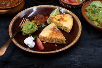 Mexican skillet cornbread served with tomato salsa and guacamole, sour cream on clay dish