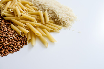 Whole grains on white table. Raw buckwheat, pasta, rice. Empty space for copy. Panic buying food products in bulk for coronavirus outbreak isolation at home. Frightened people reacting crazy in fear.