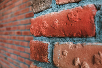 Side angle of a red brick wall corner. Close up view of cracked weathered brickwork material. Modern interior design, unique perspective. Loft like room style at home. Rusty facade architecture.