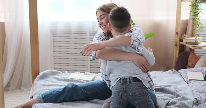 Mother with son having fun playing and tickling on bed