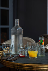 Natural Still Life on Table in Cafe - Drinking Water Faceted Bottle Glasses with Orange Juice Napkins Knife and Fork