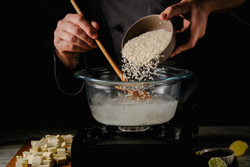 the cook pours raw rice into the pan. High quality photo