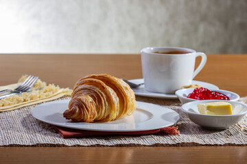 Breakfast with Croissants and a cup of coffee, accompanied by a newspaper. Croissants with strawberry jam and butter.