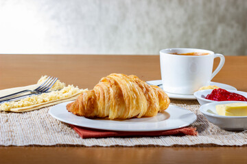 Breakfast with Croissants and a cup of coffee, accompanied by a newspaper. Croissants with strawberry jam and butter.