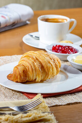 Breakfast with Croissants and a cup of coffee, accompanied by a newspaper. Croissants with strawberry jam and butter.