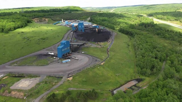 Aerial push in showing coal trucks pulling into a coal elevator machine and piles of coal in Mt Storm, WV.
