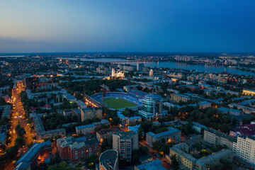 Voronezh city center in evening with stadium, roads and many buildings, aerial view.