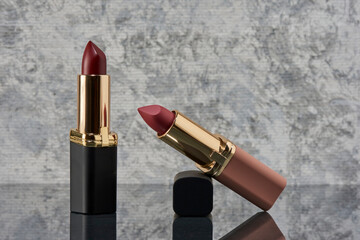 Lápiz labial Rojo con negro y rosa sobre una superficie de mármol con las tapas tiradas al...