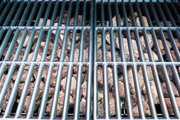 Obraz premium New and clean barbecue grill with lava rocks for gas cooking.