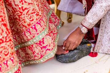 Groom wearing the ring on bride's toe finger, traditional indian hindu wedding ritual during marriage ceremony  