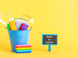 A metal bucket with highlighter marker pen and school ruler on a blue background.