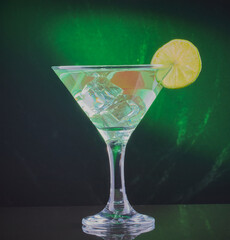 Still life of a cocktail on a dark background ,highlighted with a green light beam.