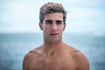 Portrait of young man, surfer and blue ocean on background