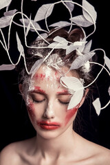 Asian woman with white branches and red lipstick doing makeup face styling in black background