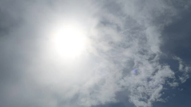 B-roll cinemagraph TimeLapse of Bright glowing sun light with sunbeam, flare & rainbow rays on beautiful sunrise sky background with pink wispy smoke cloud & cloudscape in tropical summer sunshine day