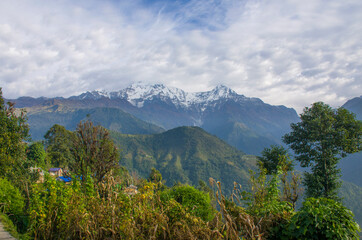 The peaks of the mountains of Nepal among the trees are the landscape of the Himalayas
