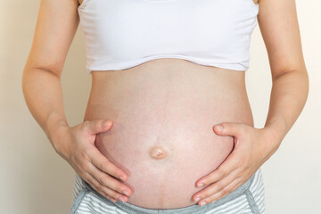 The pregnant woman touches her belly.