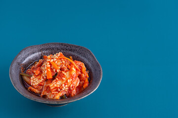 Traditional Korean dishes (Kimchi) in a bowl on blue background.