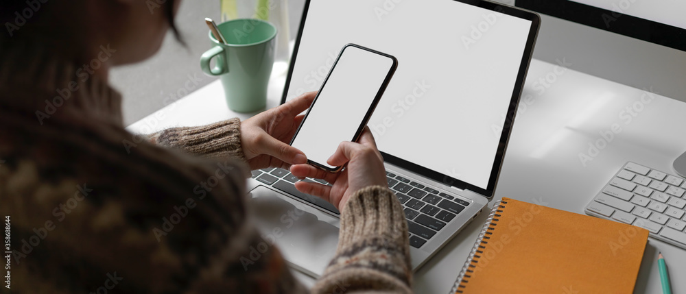 Poster female university student looking information on mock-up smartphone while doing assignment on mock-u