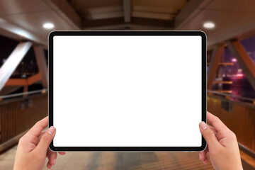 Two hands holding white screen mockup tablet computer on Hong Kong human bridge at night
