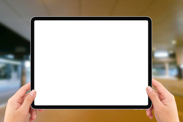 Two hands holding white screen mockup tablet computer in airport terminal traffic station